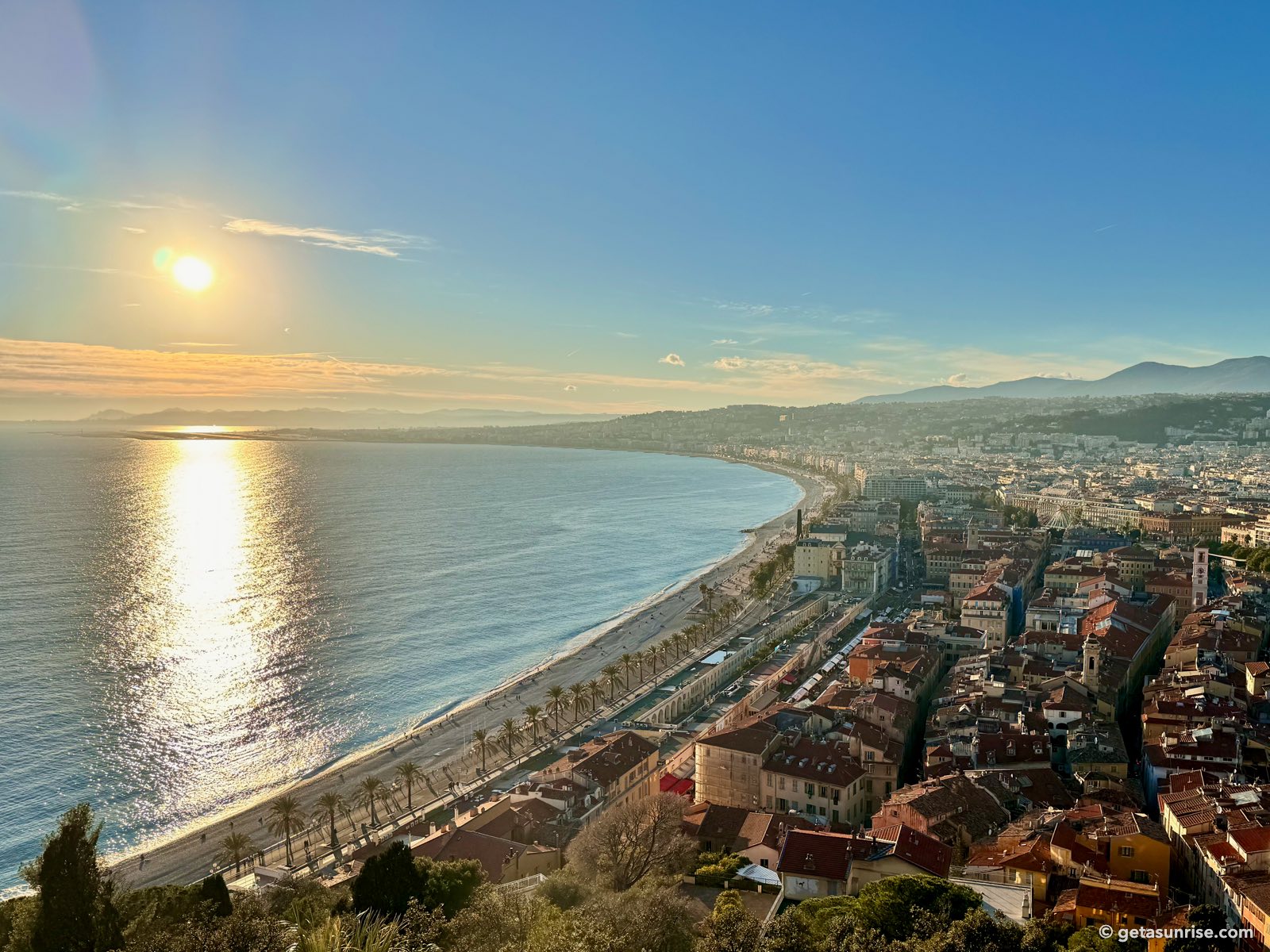 The low winter sun over the Baie des Anges seen from Castle Hill, with its reflection on the sea, the Promenade des Anglais and the Old Town of Nice