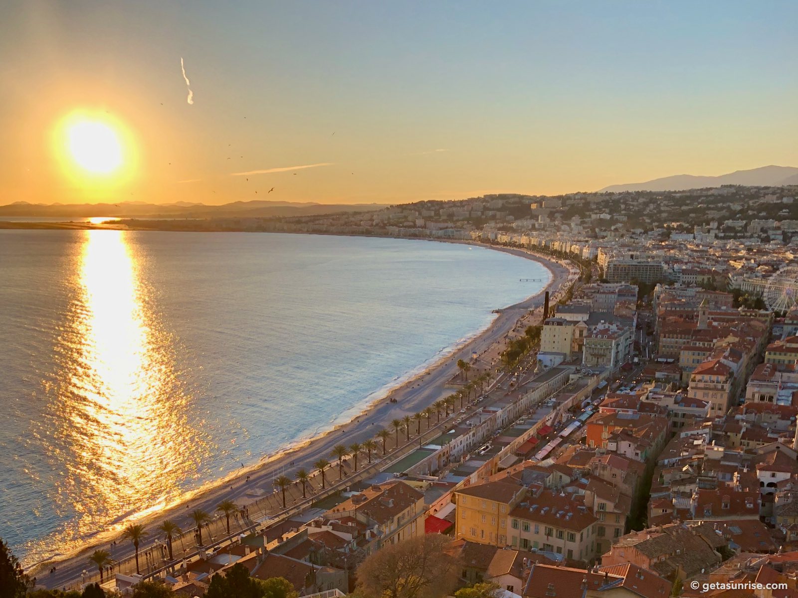 Golden sunset over the Baie des Anges from Castle Hill in Nice, the sun above the hills beyond the airport
