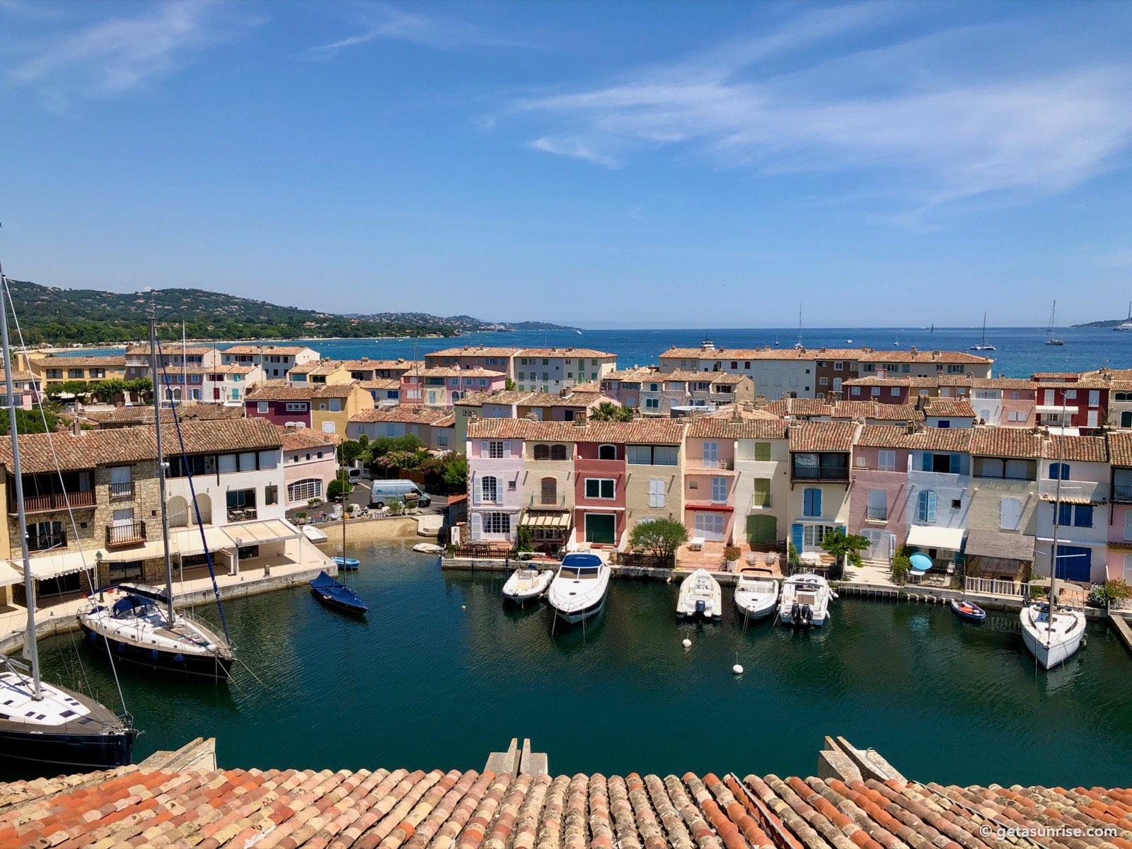 Canals and colourful houses of Port Grimaud, with the Gulf of Saint-Tropez and the hills of Sainte-Maxime in the background